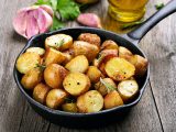 Roasted potato in frying pan on wooden background